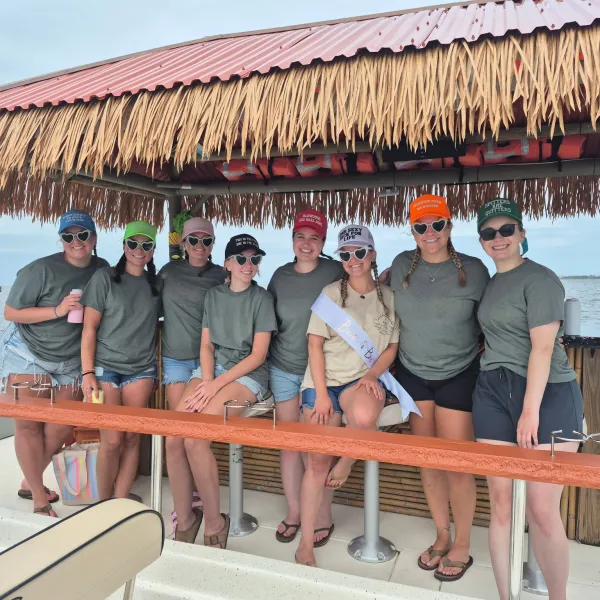 Group of women in matching outfits on a tiki boat smiling at the camera.