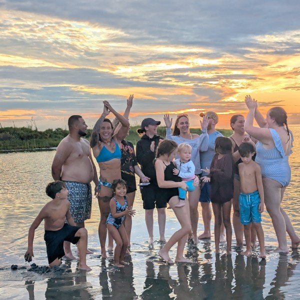 Group of people celebrating on the beach at sunset.