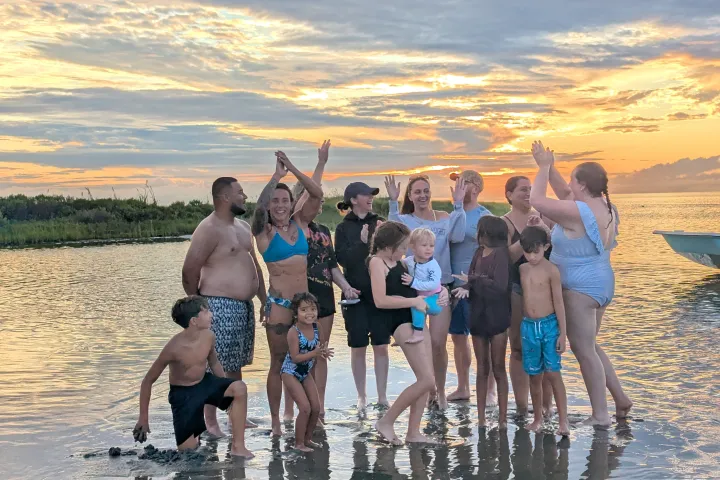 Group of people celebrating on the beach at sunset.