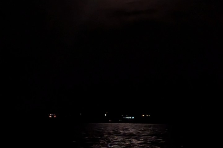 Full moon illuminating dark night sky and reflecting on water.